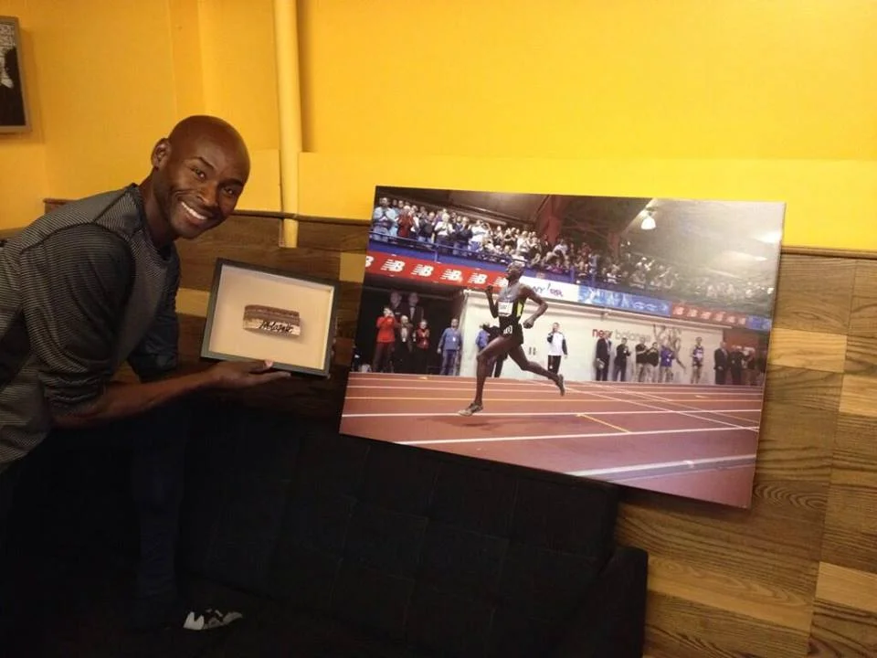 Bernard Lagat poses with an autographed piece of The Armory's track, which will be raffled off at Saturday's NYRR Millrose Games. Enter to win here .
