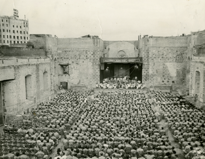 Gelatin Silver Print: U.S. Army Signal Corps, May 9, 1945. “Liberation Concert” with Herbert Zipper conducting the Manila Symphony Orchestra in the ruins of Santa Cruz Church, Manila, The Philippines. From the collection of The Herbert Zipper Archives, Crossroads School for Arts & Sciences.