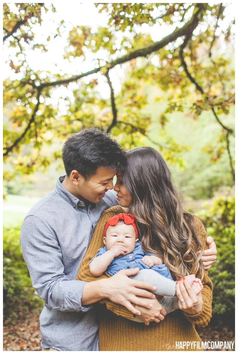 mom and dad holding baby cuddling autumn leaves - Seattle Family Holiday Portraits - the Happy Film Company