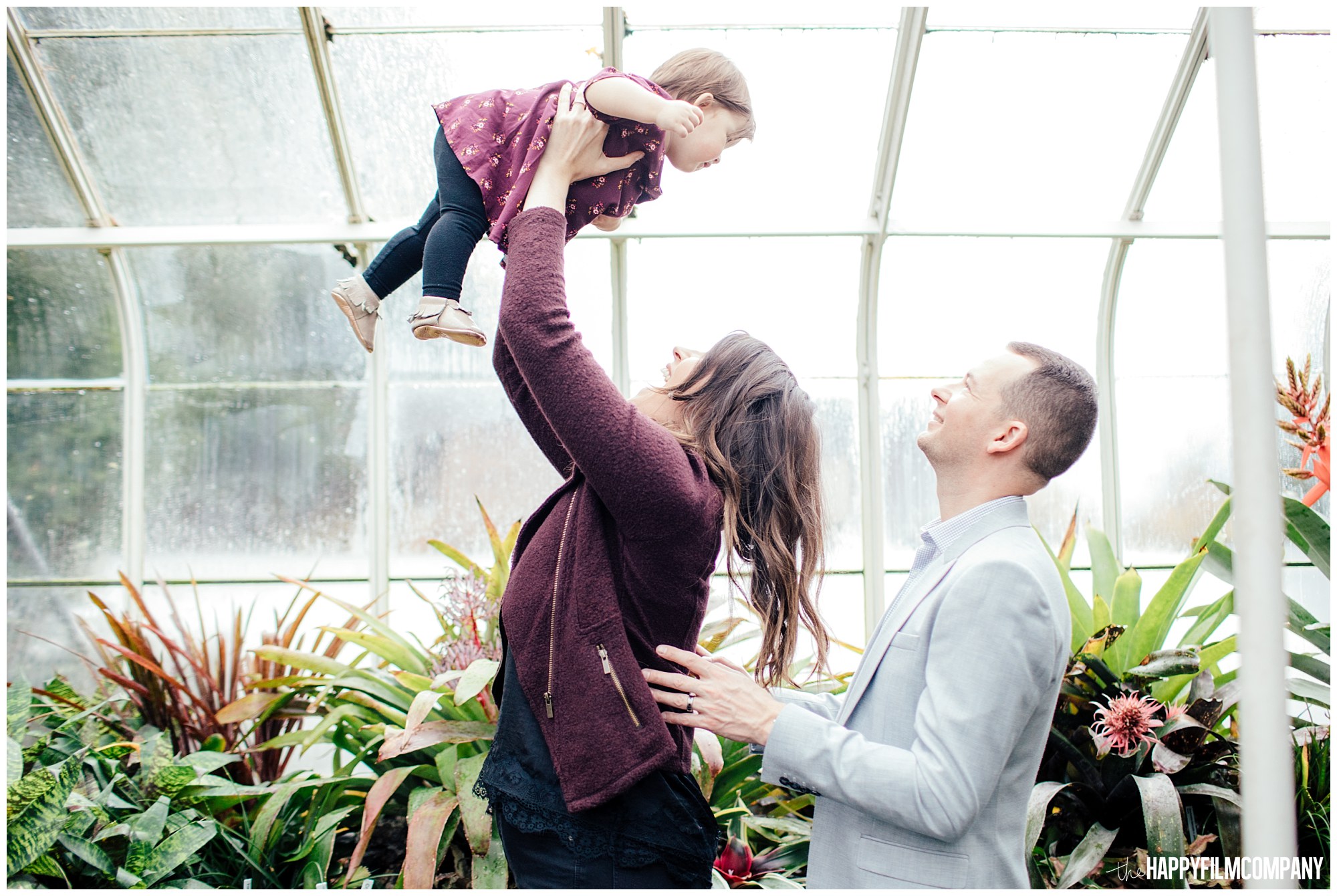 the Happy Film Company - Seattle Family Photos - Volunteer Park Conservatory - holding baby up in the air in greenhouse