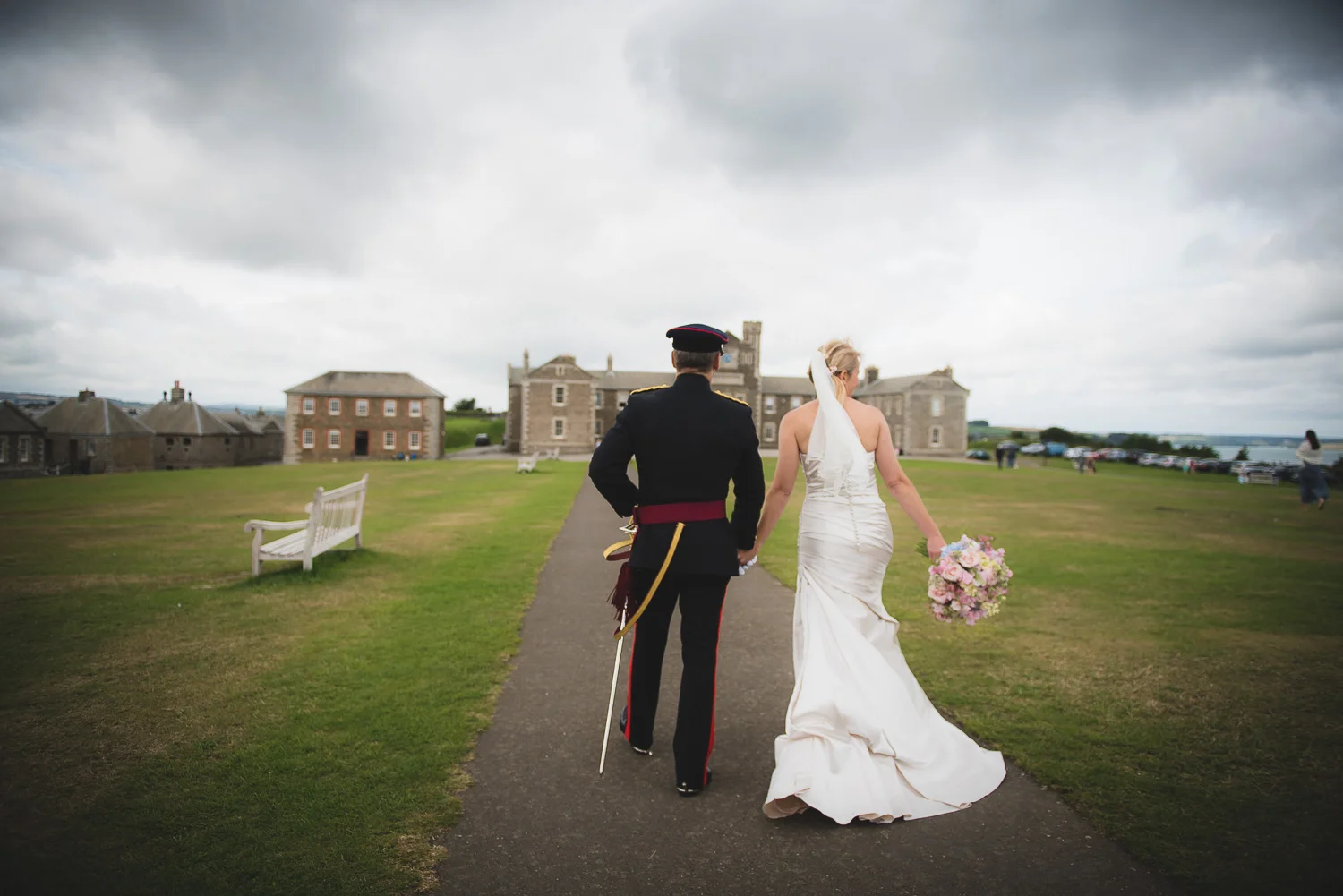 bride and groom walking away from pendennis castle in cornwall