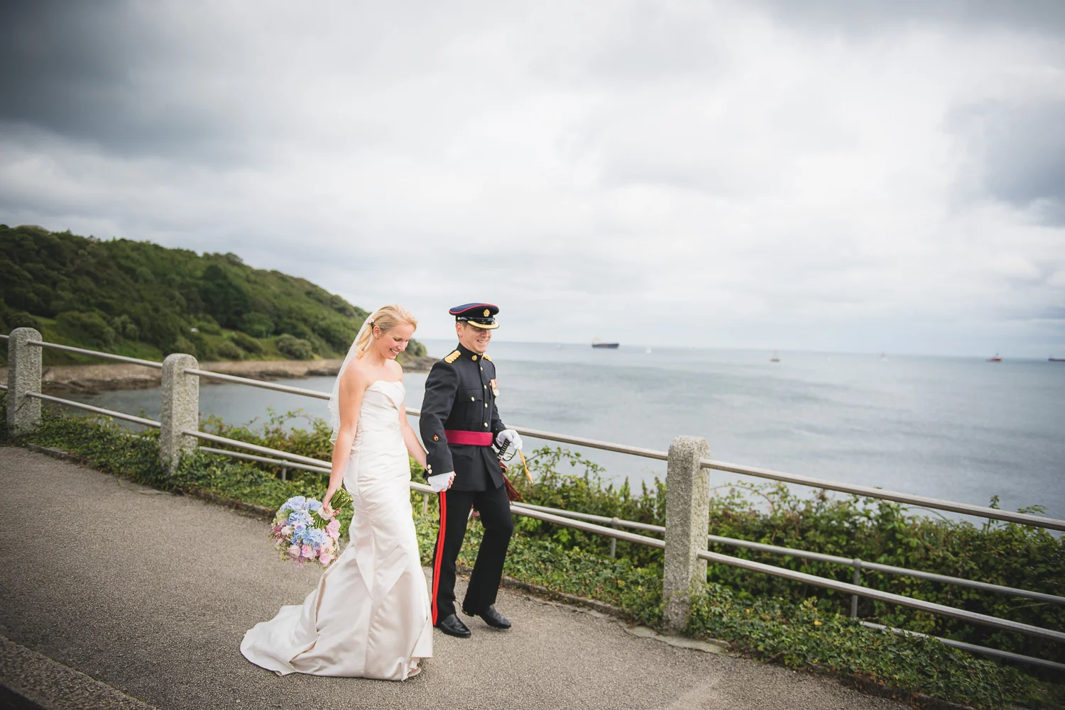 romantic documentary image of bride and groom walking by seaside in cornwall