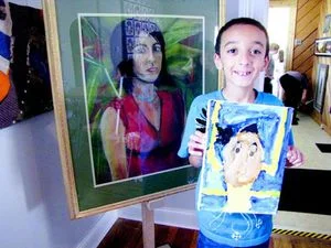   Anthony Taliaferro, 7, displays his self-portrait next to one that teacher Vanessa DeYoung created when she was in college.  