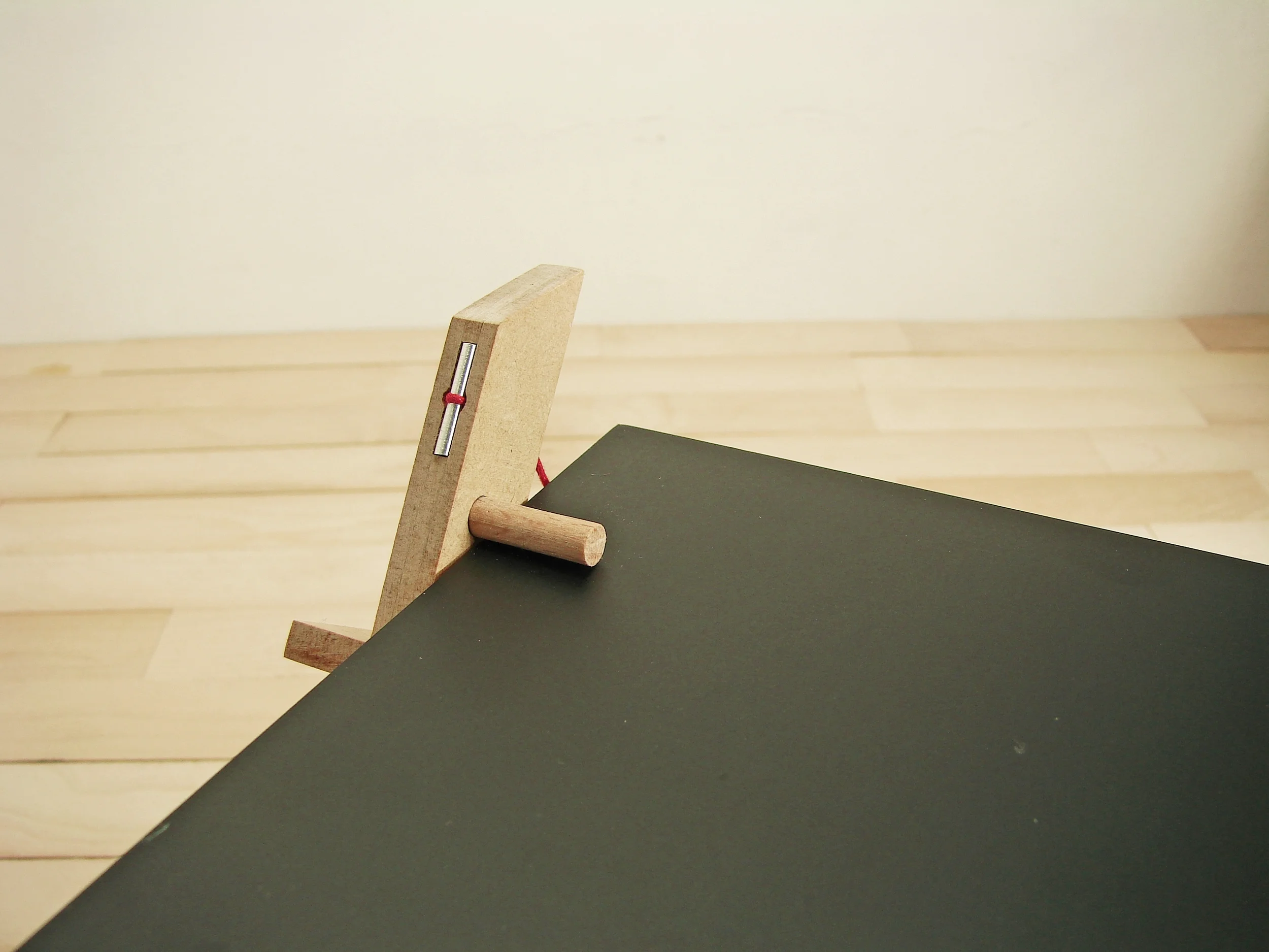   The table constitutes two legs on either side held only by an interlocking beam running across below the table top, the table top sits on this and below the two wood pegs on either sides. But the real element which brings the whole assembly alive i