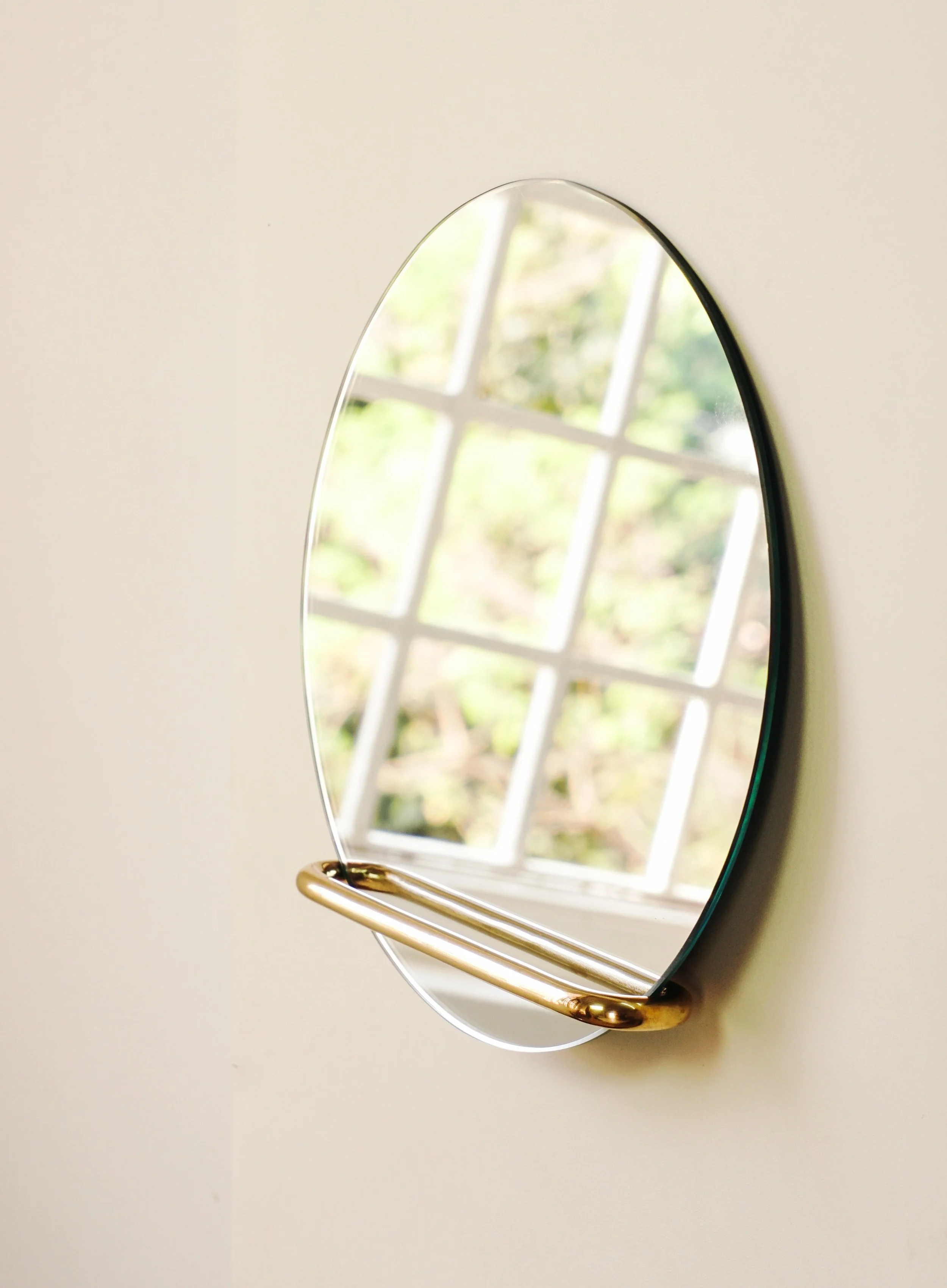 NOŪR MIRROR The mirror is as essential as it comes, its has strong geometry yet soft and unobtrusive. of it is it just rests on a small brass loop bracket on the wall, which is last in a series of minimal soft shape which we did after our Bracket Trays and LOUP, which we recently did for OTHR . The beauty is that loop gets reflected back into the mirror to complete its shape as reflection, making it quite mesmerizing if you notice the subtle detail. The mirror is loosley slid into the bracket to hang on the wall, this gives it an ease to be removed and cleaned, it is available in two variations - a circular and a soft square. 