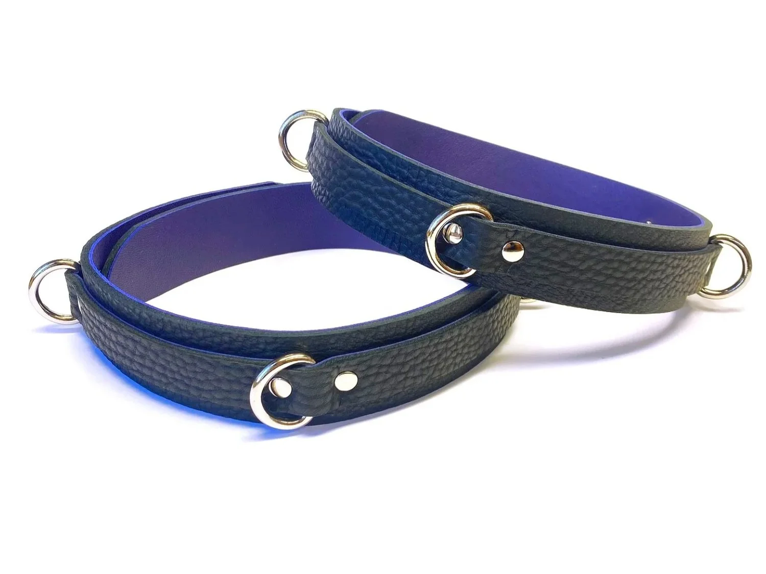pair of leather thigh cuffs with triple d-rings in black bullhide lined with purple lambskin