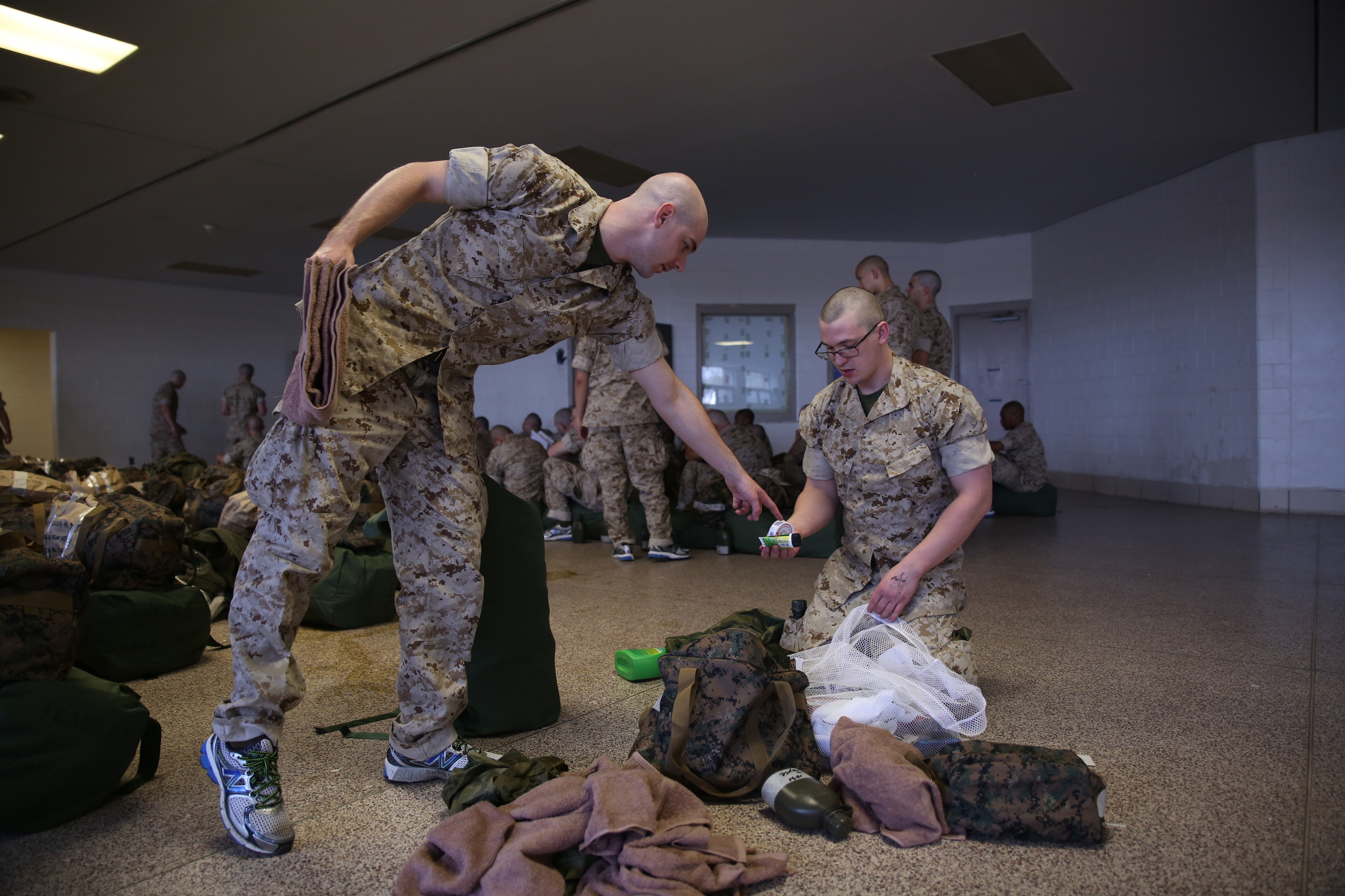 A Marine Corps recruit instructs another how to organize his things. Photo by Cpl. Octavia Davis, United States Marine Corps.