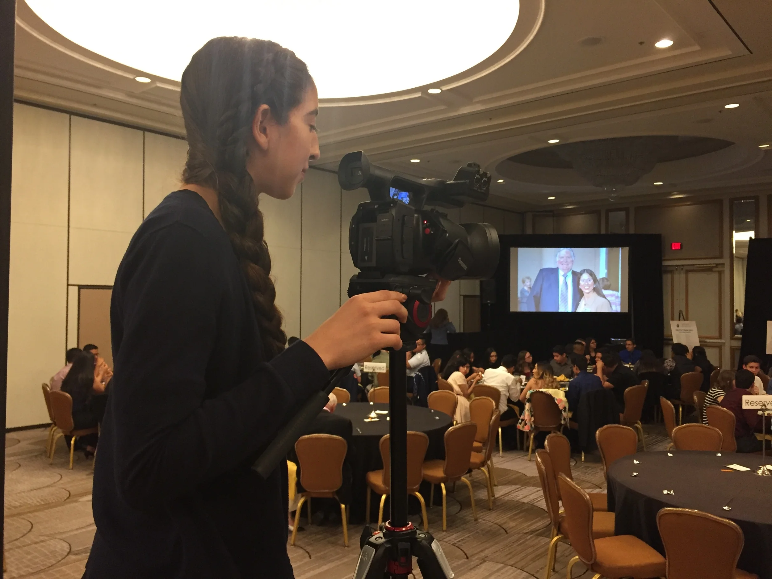 DATA Junior Jennifer Reynoso operates the main camera for David Petraeus' Youth Town Hall. 
