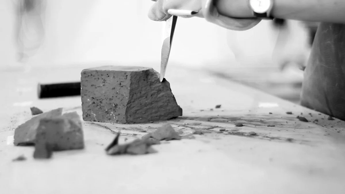 Breaking the brick with a chisel.