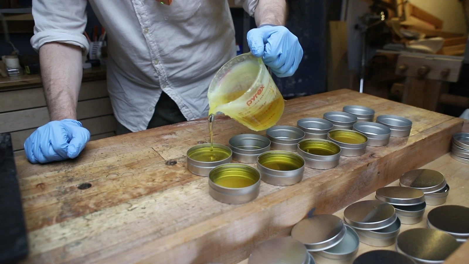 Pouring warm beeswax and oil polish into metal tins