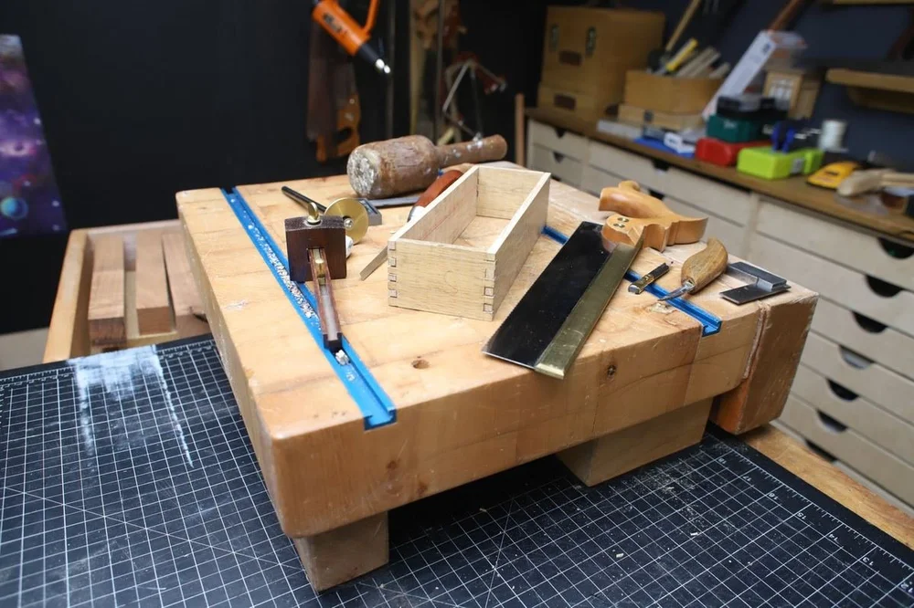 The dry-fitted carcass with the saw, gauge, dividers, and chisel