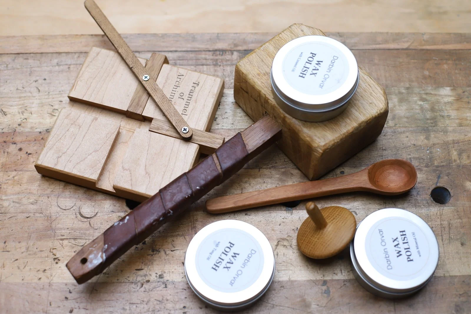 Handmade beeswax polish tins and wooden projects arranged on the workbench