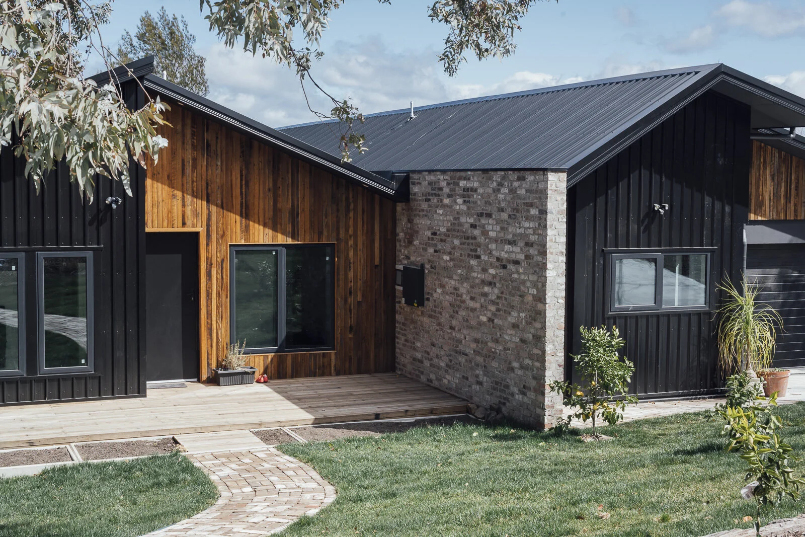 The black insulated panels, recycled Blackbutt cladding & decking, and double glazed windows.