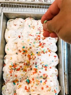 sprinkling fruity cereal on top of finished cereal milk buns.jpg