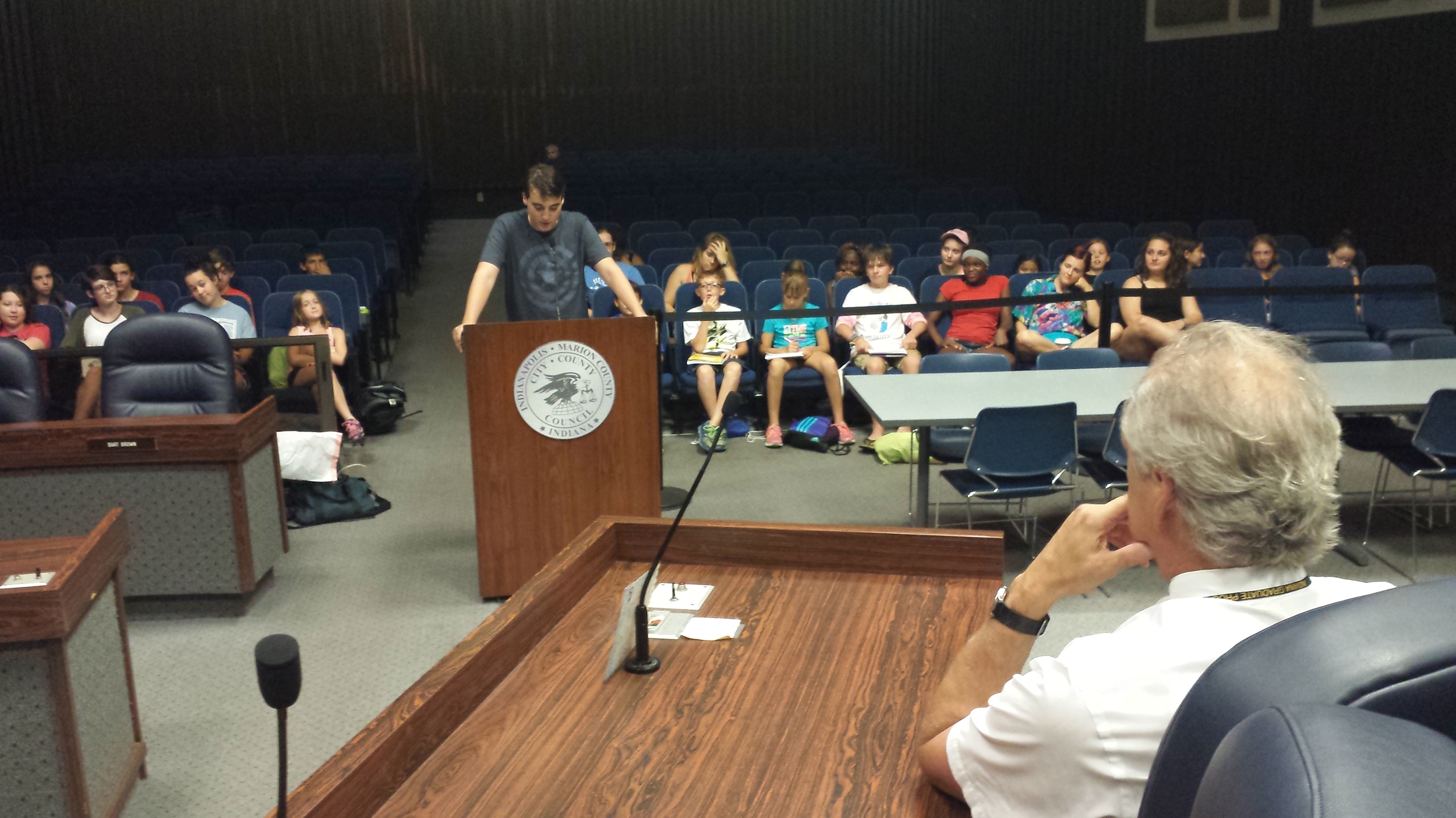 Ben, 15, from International School of Indiana, testifies to, in the foreground, Judge David Dreyer.