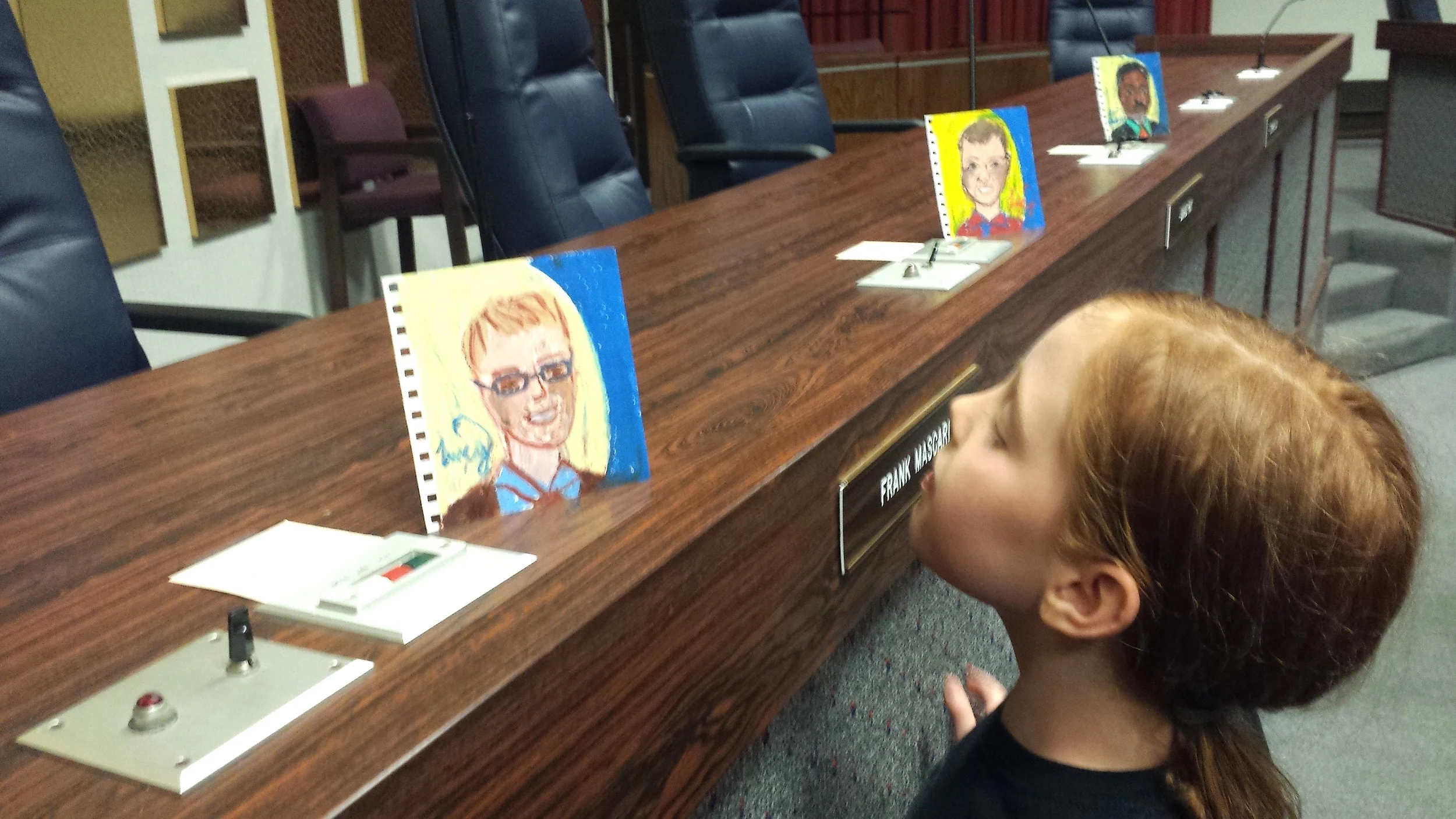 Ella, a student at School 91, inspects Lucy's portrait work.