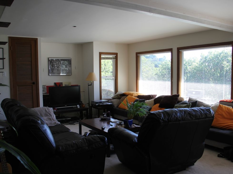 Before: The living room, while full of windows and natural light, feels dark and heavy due to the oversized furniture and limited pathways.