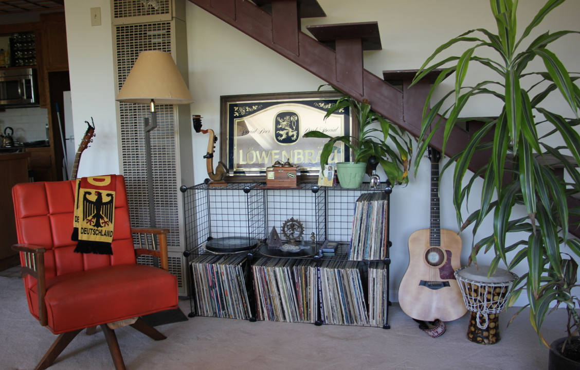 After: The orange chair provides a more proportional seating option, better access to Greg's musical instruments and records, as well as adding a pop of visual interest to the room.