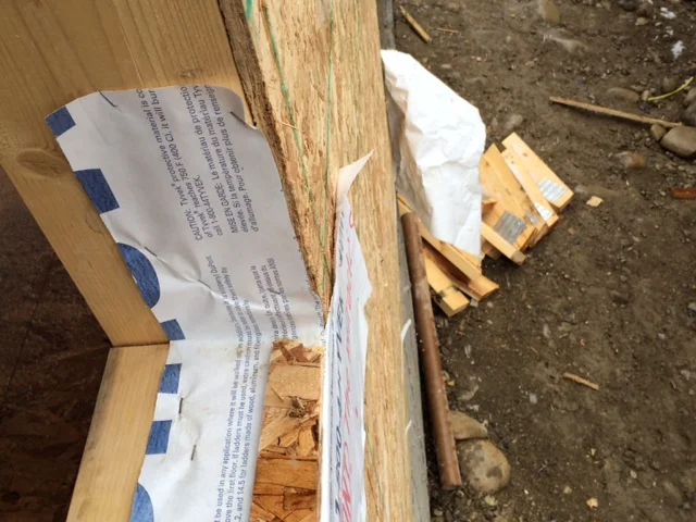Building paper stapled to window frame - THE WRONG WAY