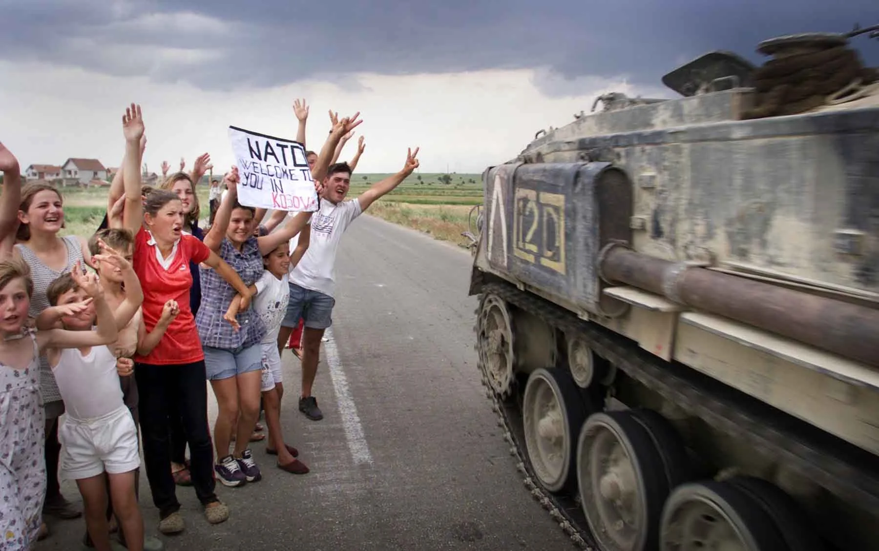 1999 Children greet British troops as they arrive on the outskirts of Pristina. Kosovo.