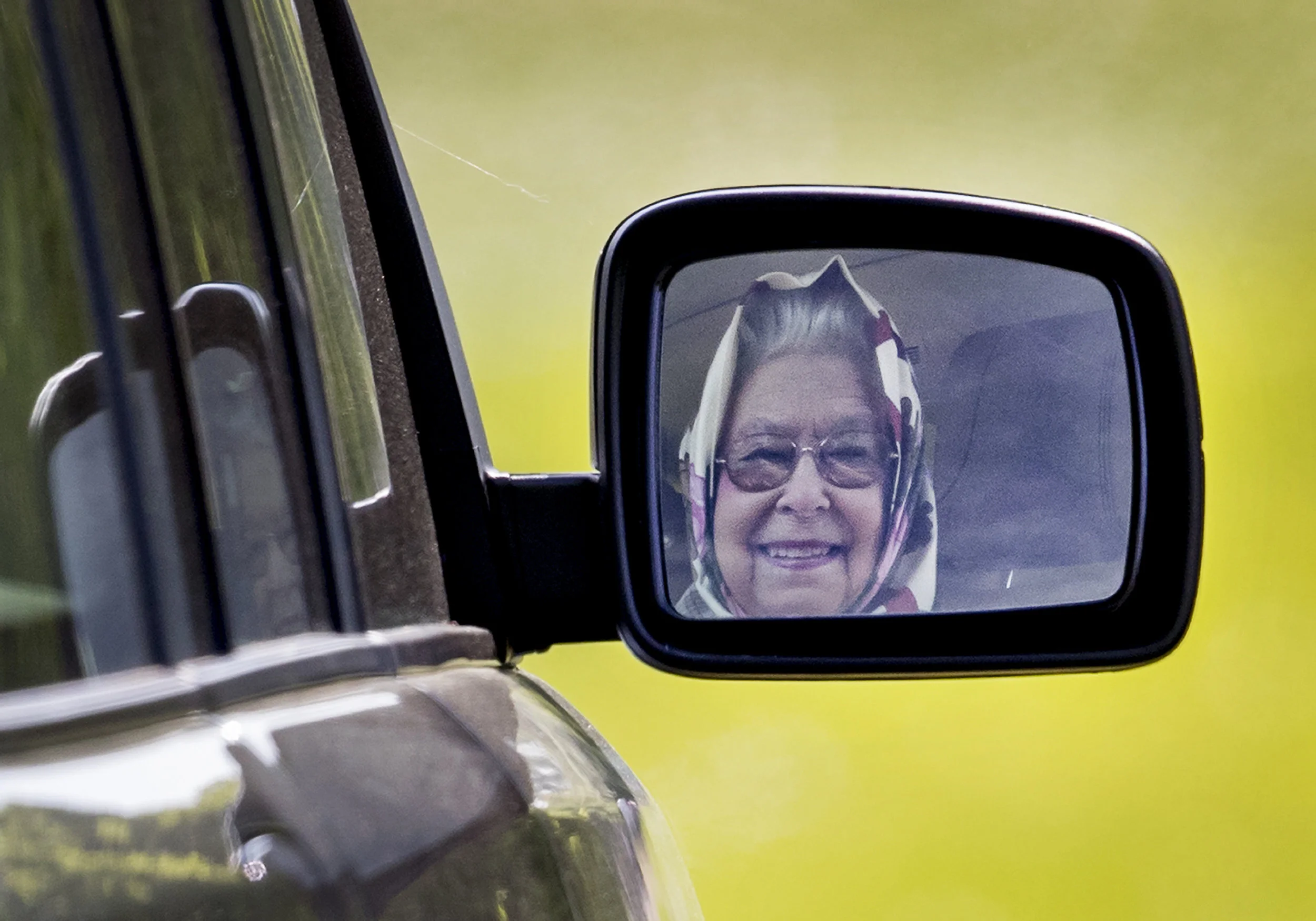 2017. Queen Elizabeth II is reflected in her mirror as she drives from the Royal Windsor Horse Show. Windsor, England.