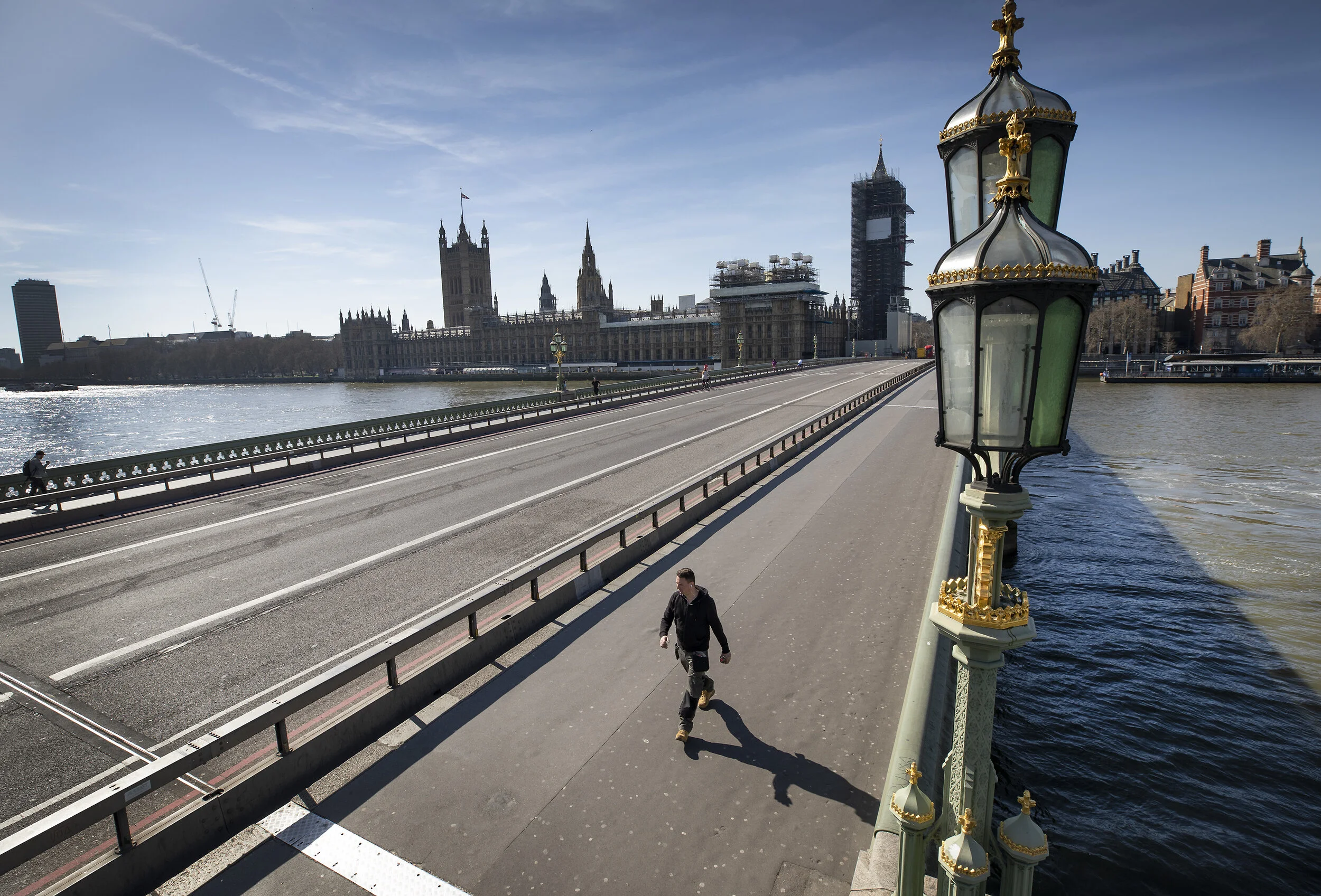 A few pedestrians can be seen on an almost deserted Westminster Bridge at 1:14pm after Prime Minister Boris Johnson announced that the UK will now lockdown on March 24, 2020.