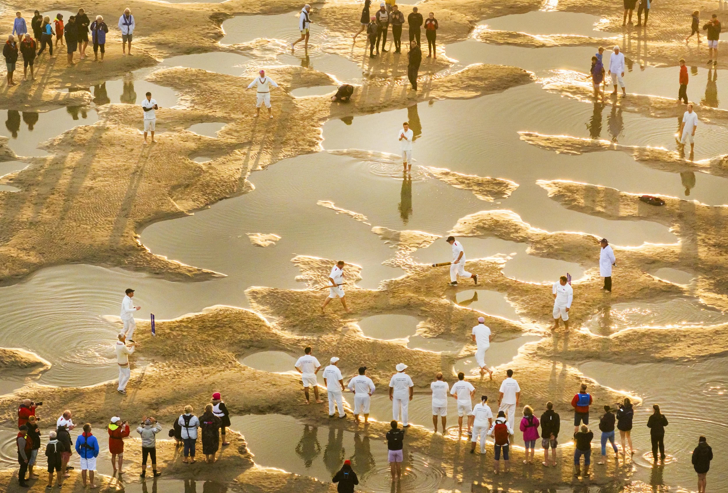 Sailing club teams play a cricket match at sunrise on Bramble Bank sandbank which appears for 30-60 minutes at low tide in the middle of The Solent on September 2, 2023.