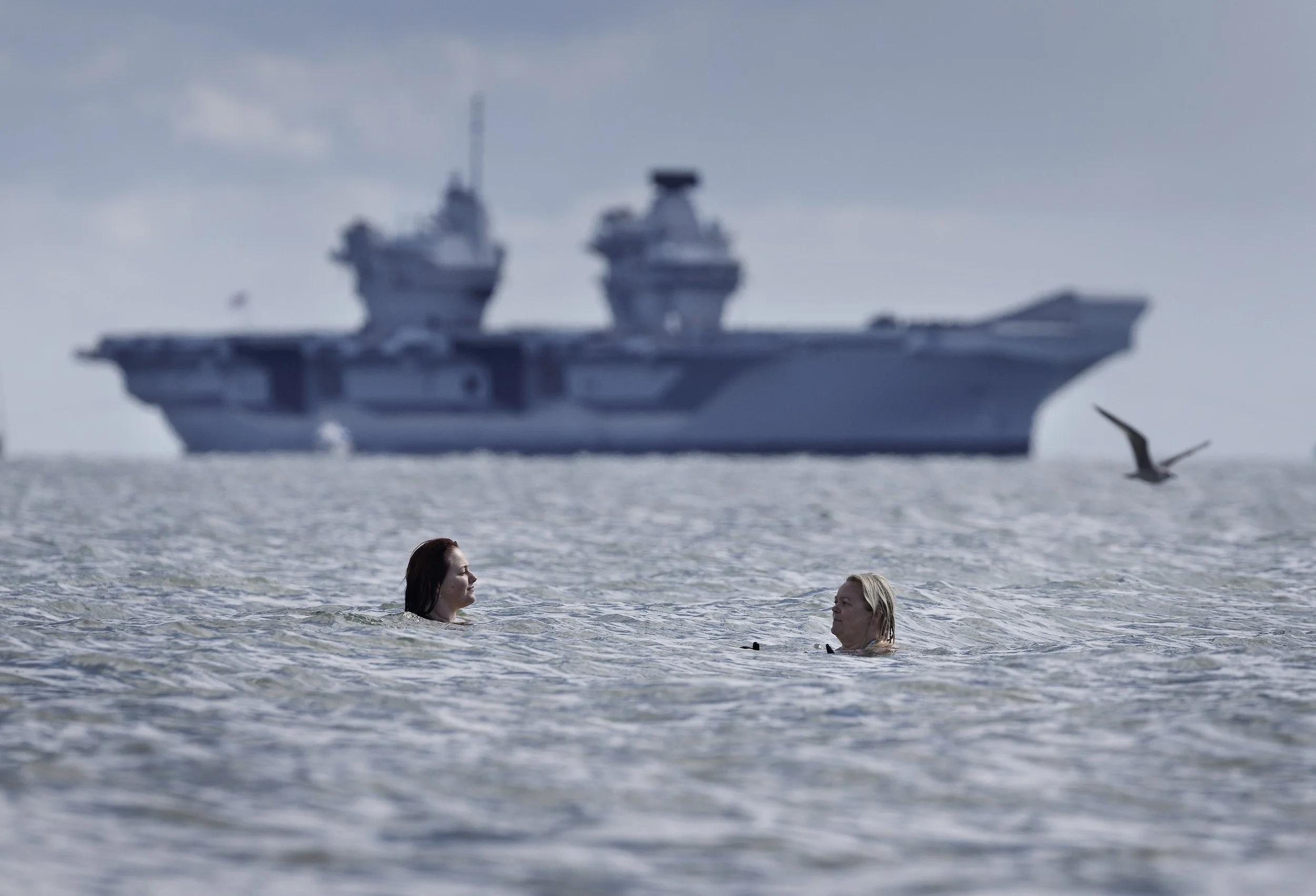 Swimmers exercise as Royal Navy aircraft carrier HMS Queen Elizabeth arrives in The Solent after completing operational sea training on September 12, 2024.
