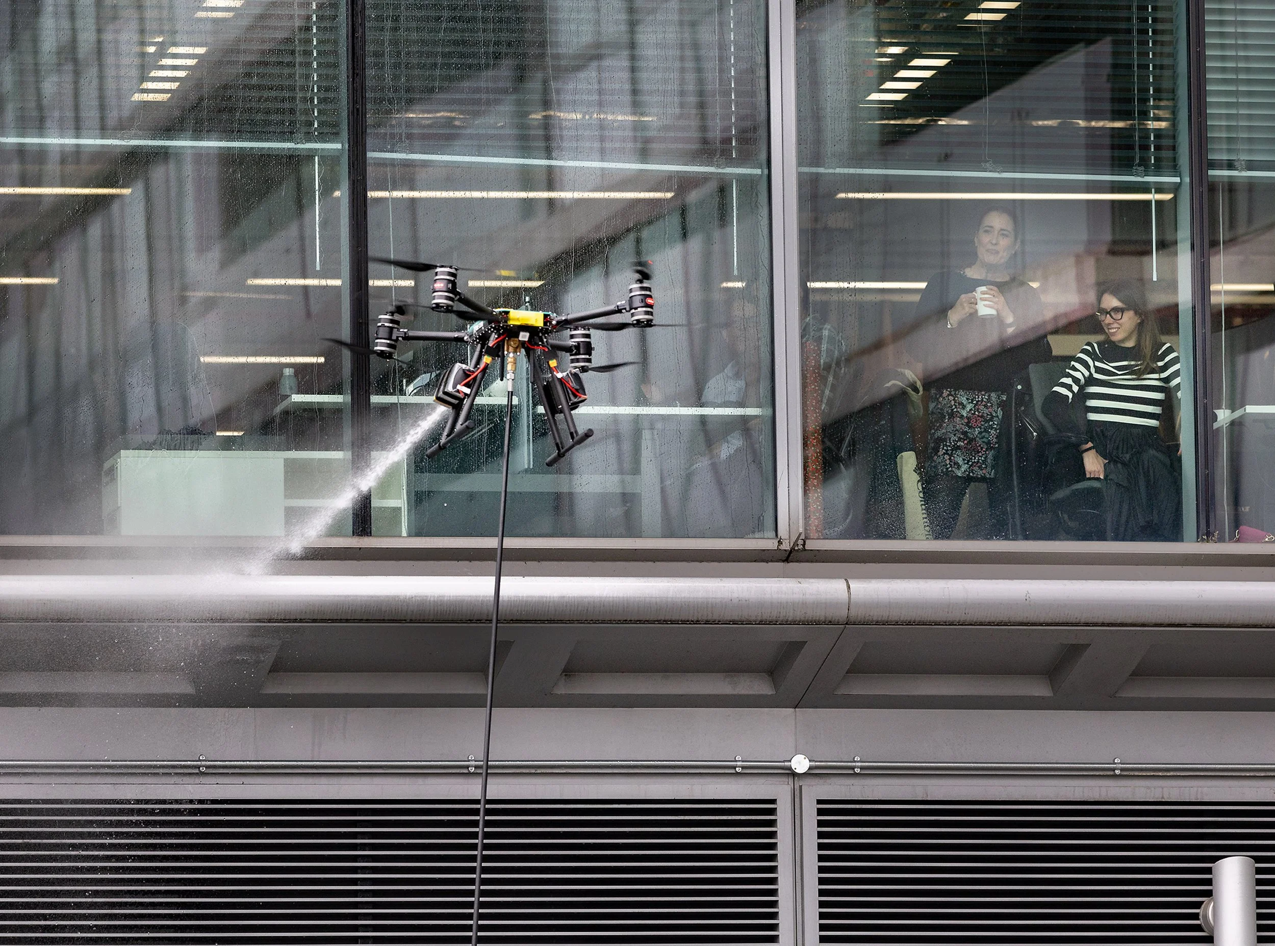 Office workers look on as a drone cleans windows in Victoria, central London on March 25, 2025.
