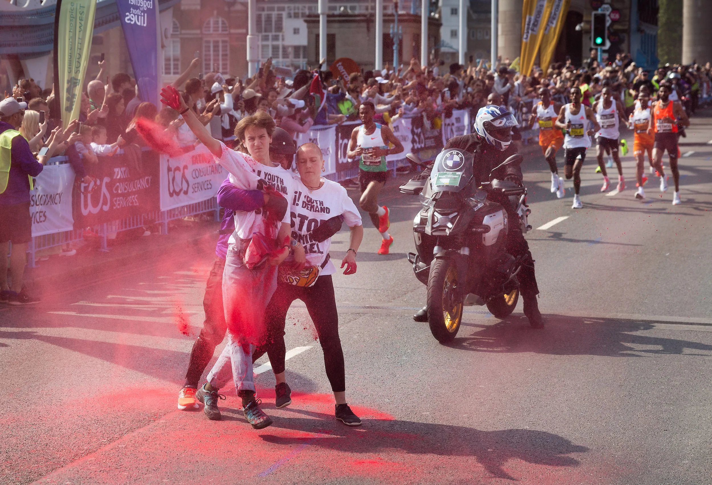 Youth Demand activists throw red powder as the men's Elite runners reach Tower Bridge during the London Marathon on April 27, 2025.