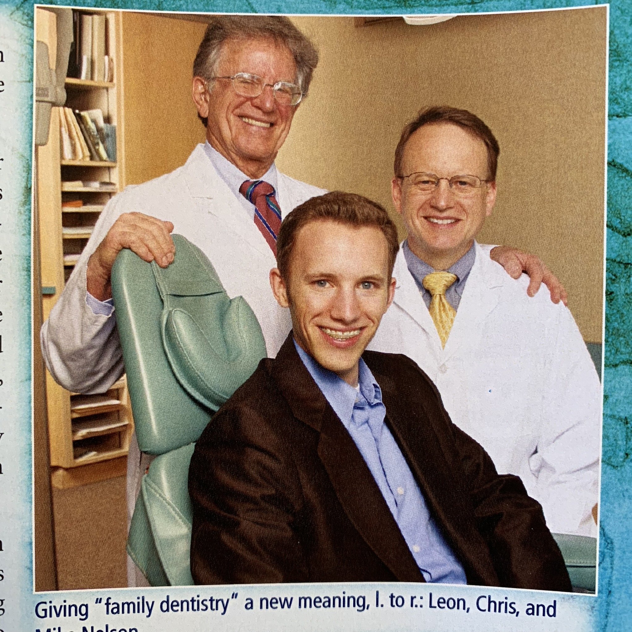 Dr. Leon Nelson, Dr. Mike Nelson and Chris Nelson DDS, two of them wearing glasses and wearing suits, one with a striped tie, seated indoors with a bookshelf in the background.