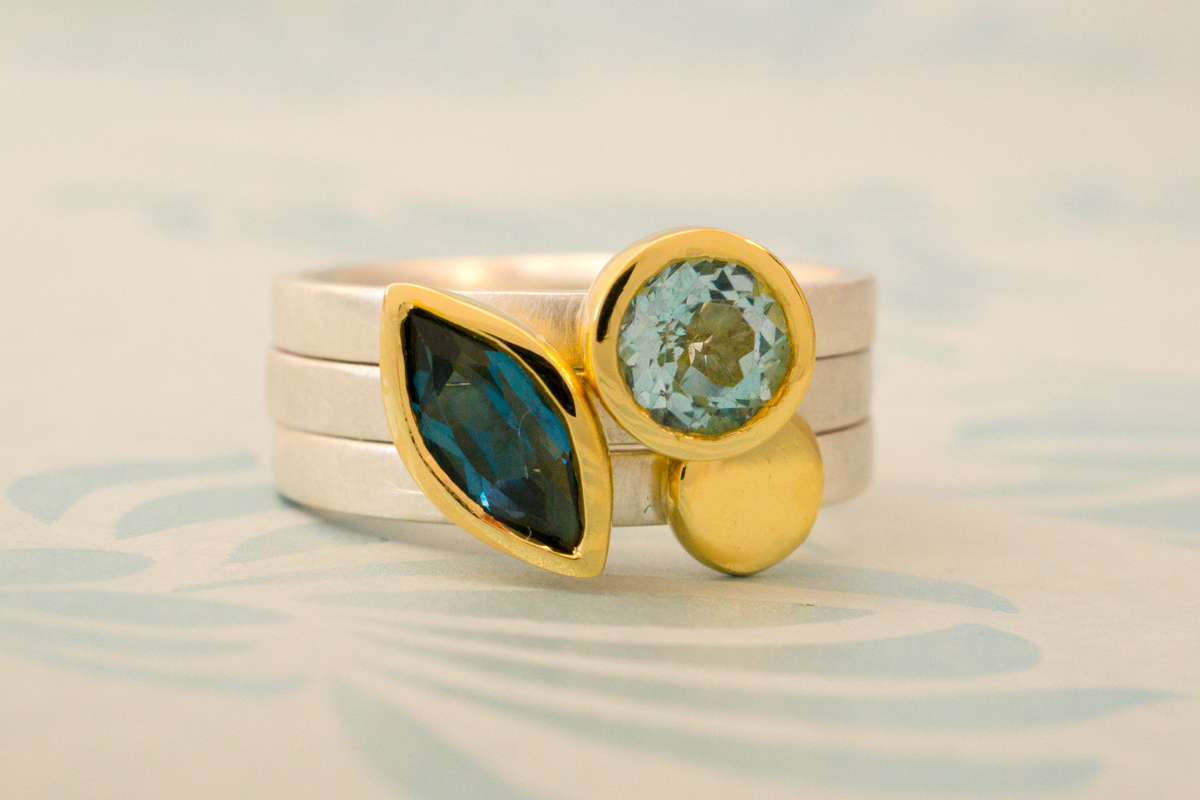 Stacking ring trio. Marquise shaped London blue topaz and round sky blue topaz set in 18 carat yellow gold, and gold nugget all on silver bands