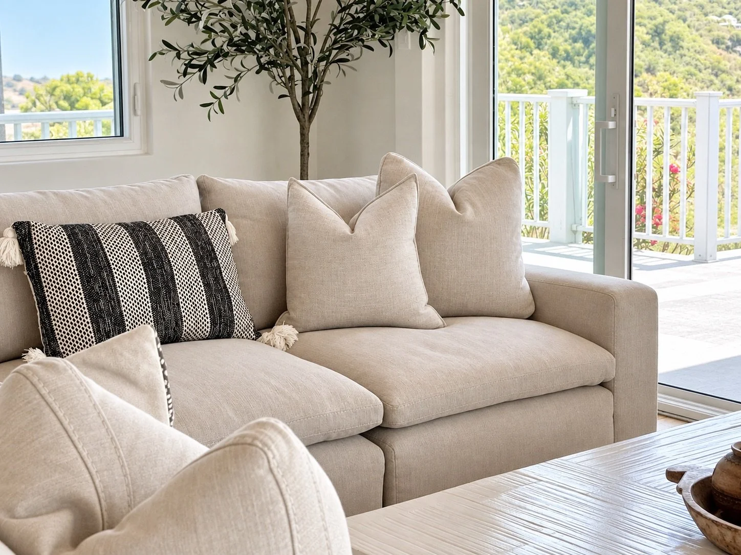 Neutral sofa styled with layered pillows and island greenery