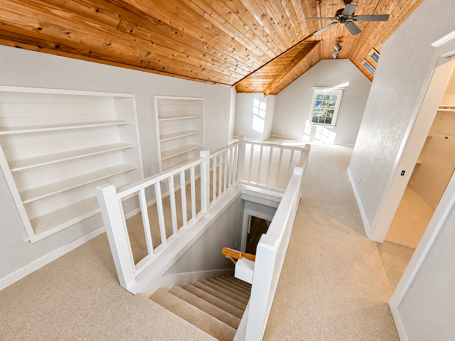 Remodeled primary bedroom featuring custom stair railings, built-in shelving, vaulted wood ceilings, and updated finishes.