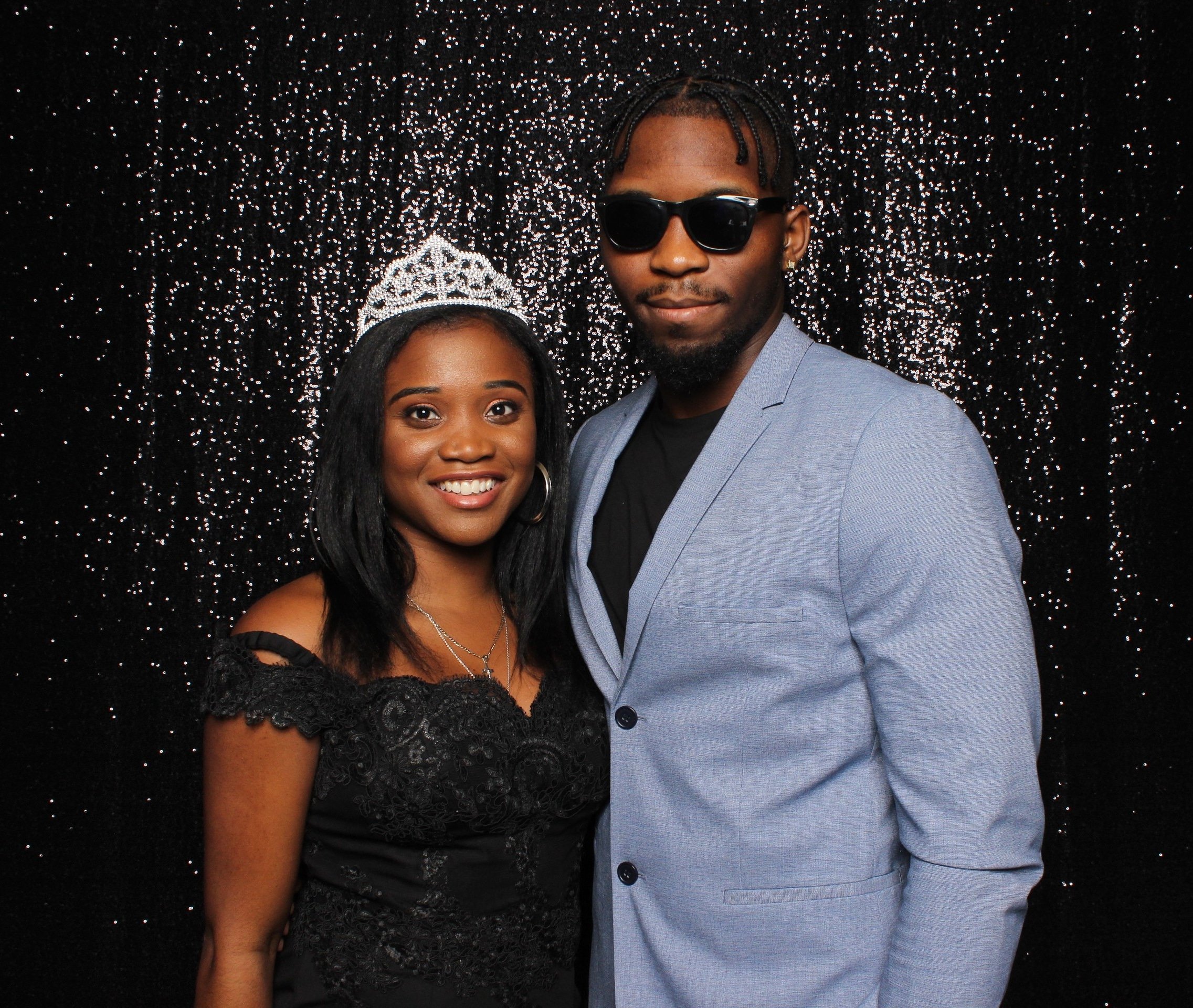  A bride and groom posing for a portrait in front of a black backdrop. 