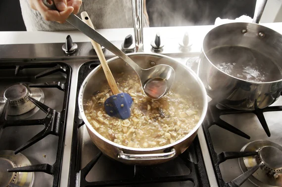 7. 讓高湯持續微滾,並開始將高湯分次加入燉飯內,每次加入的量約略蓋過米即可。燉飯保持微滾的狀態,待稍微收乾後再加入高湯,反覆這樣的動作約13-15分鐘。