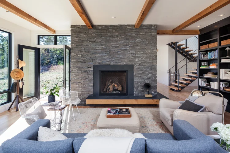 Ridgewood Residence living room with a stone fireplace and timber beams