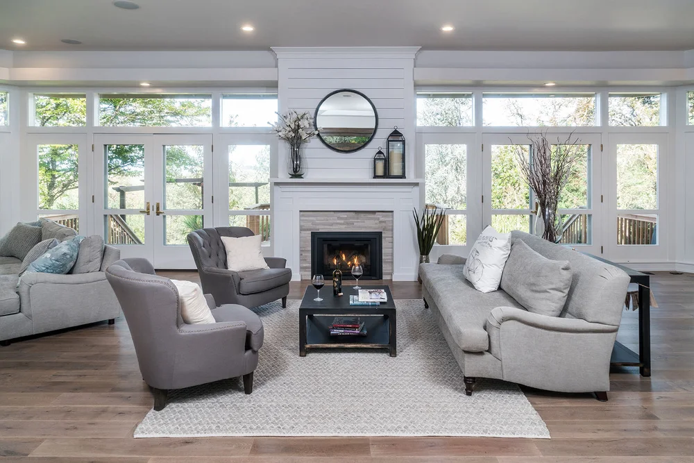 Bright living room with a white fireplace wall and tall windows
