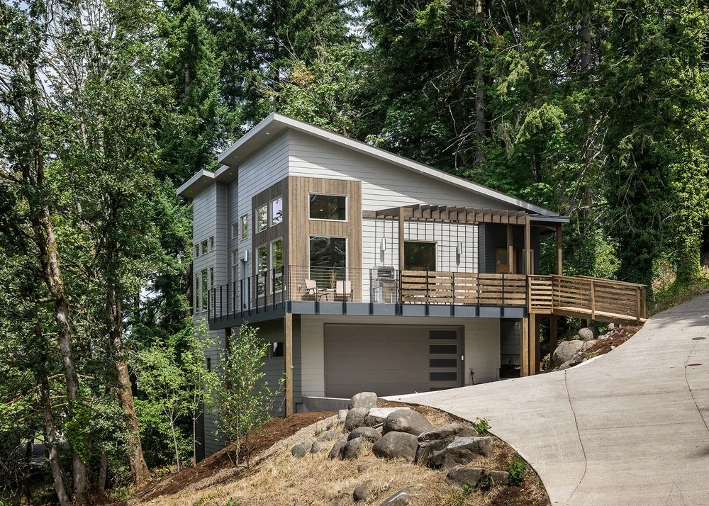 Hillside home with a shed roof and a wraparound deck among fir trees