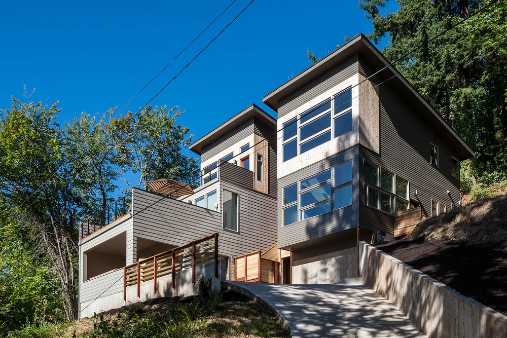 Contemporary hillside home with large windows under a blue sky