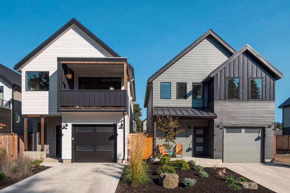 Two new homes with dark and white siding and a balcony