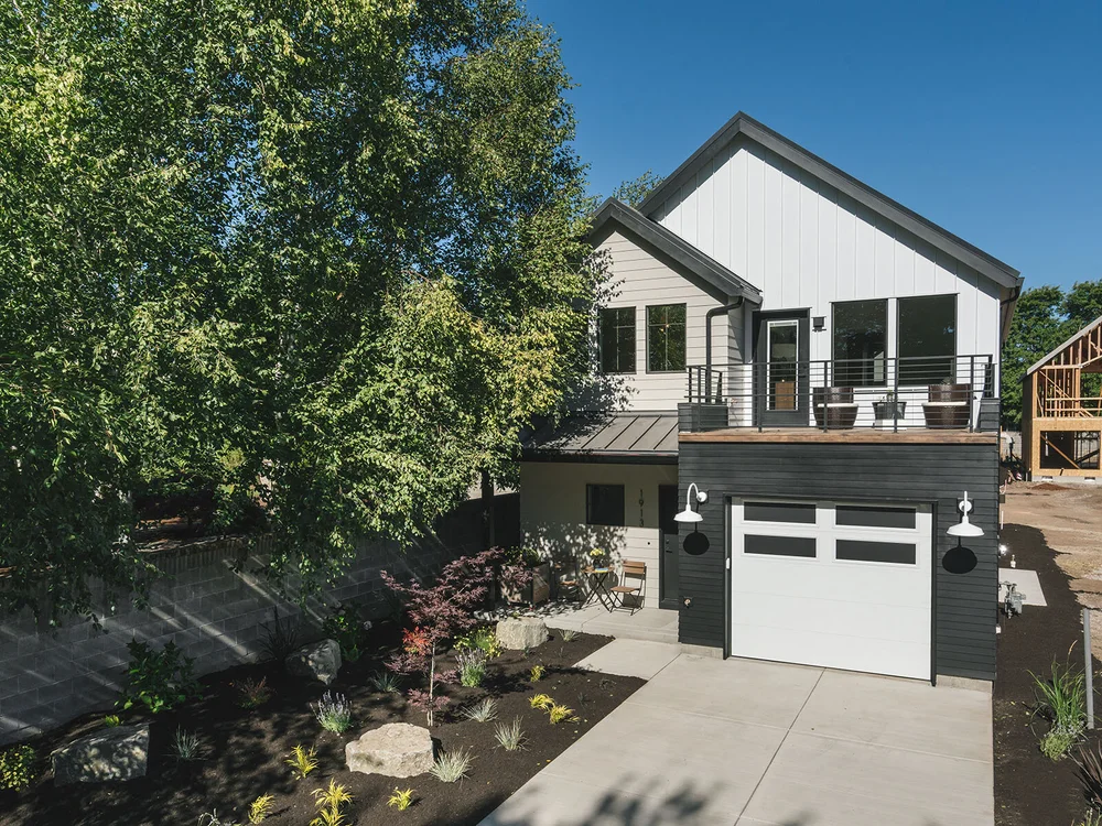 New home with a white gable and a front garage on a sunny street