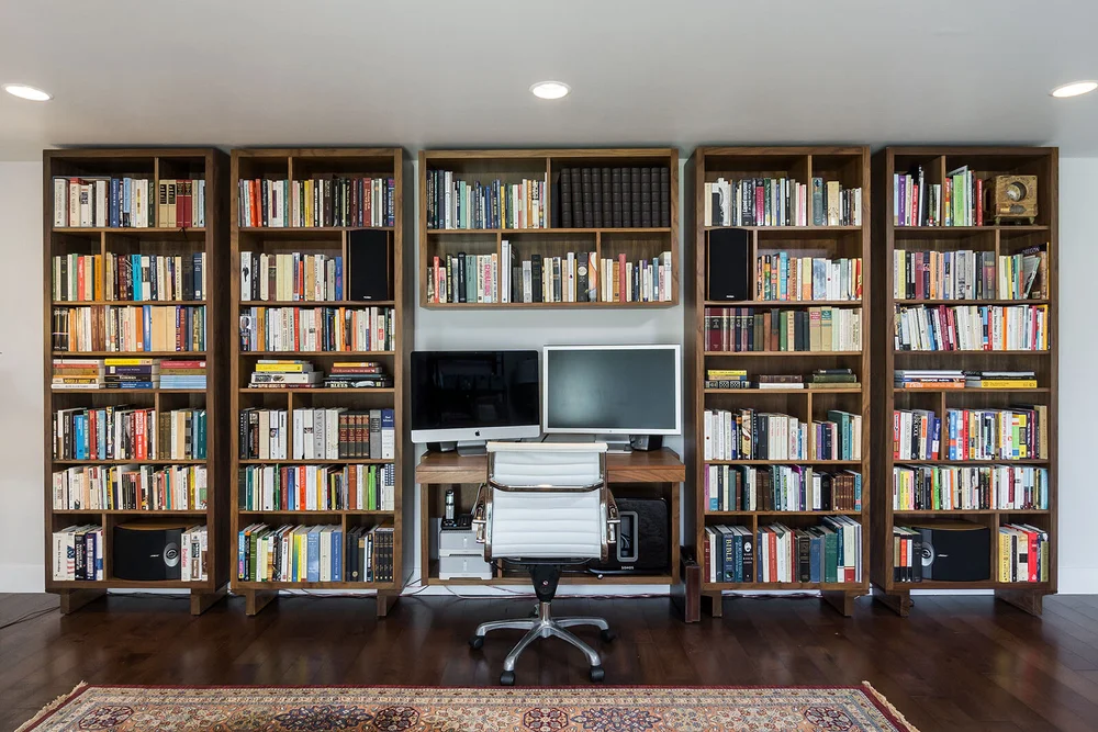 Study with floor-to-ceiling wood bookshelves around a desk