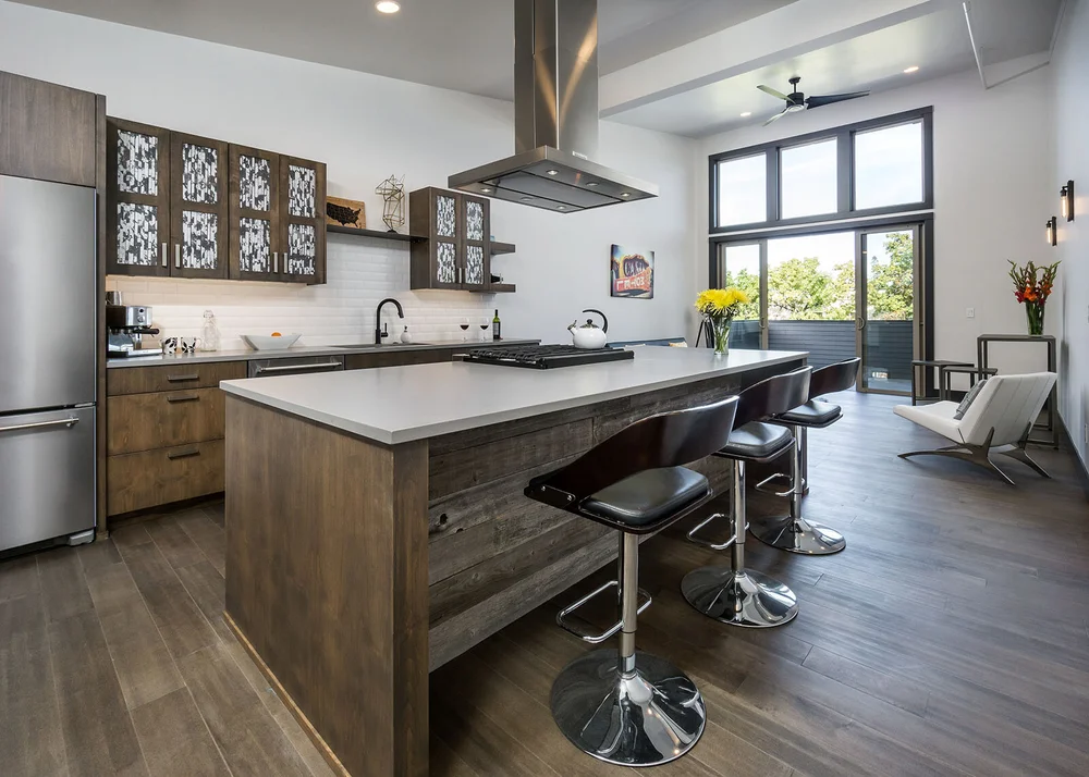 Kitchen with open shelving and a wood island under industrial pendants