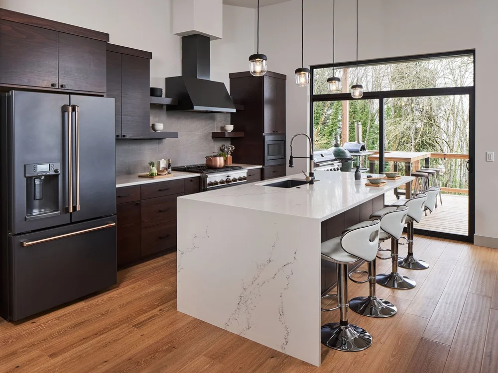Kitchen with a white waterfall island and dark cabinetry
