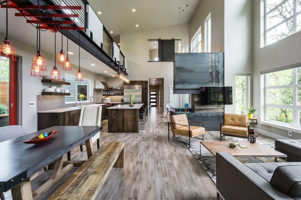 Double-height great room with red caged pendants and a blackened steel fireplace tower