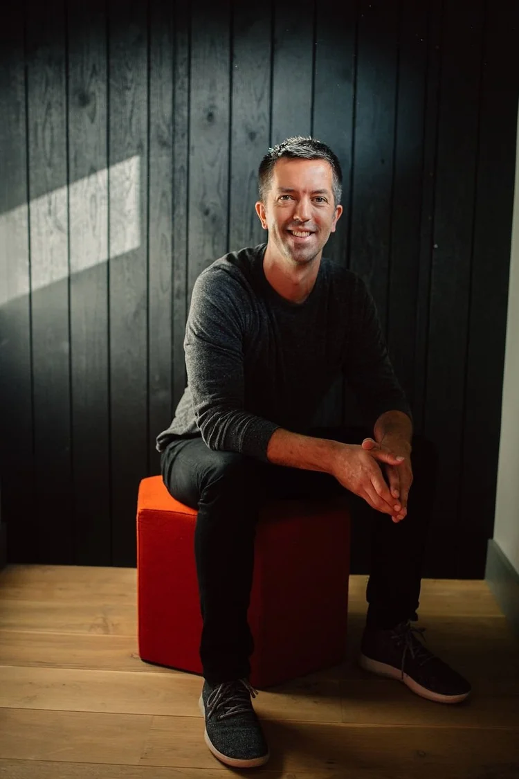 Jordan Iverson seated in front of a charred-wood wall