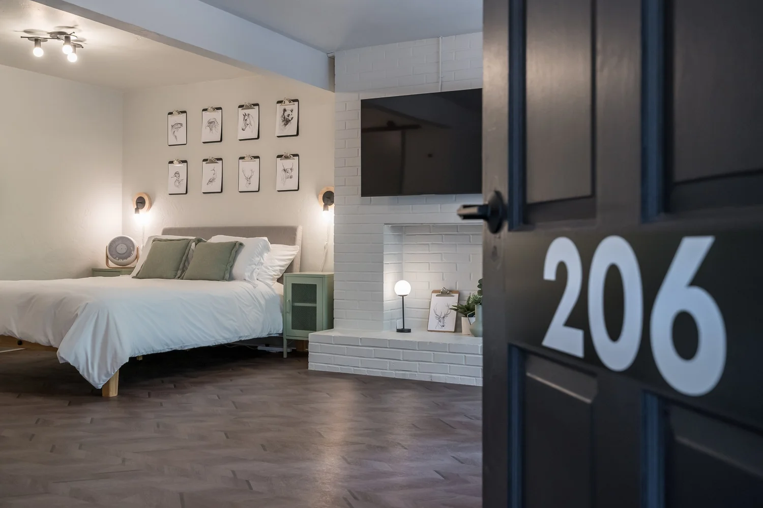Guest room at The Local with framed prints above the bed and a black door numbered 206