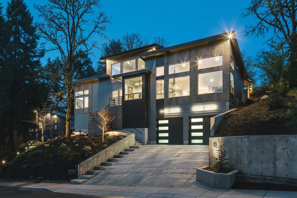 Modern hillside home at dusk with cedar and dark siding and a concrete stair