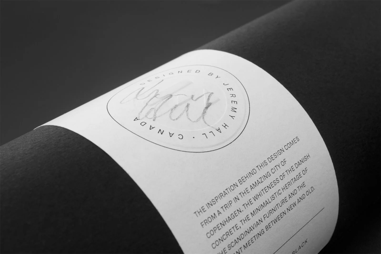 Gros plan sur une étiquette blanche avec de la typographie noir montrant une signature faite au crayon plomb.